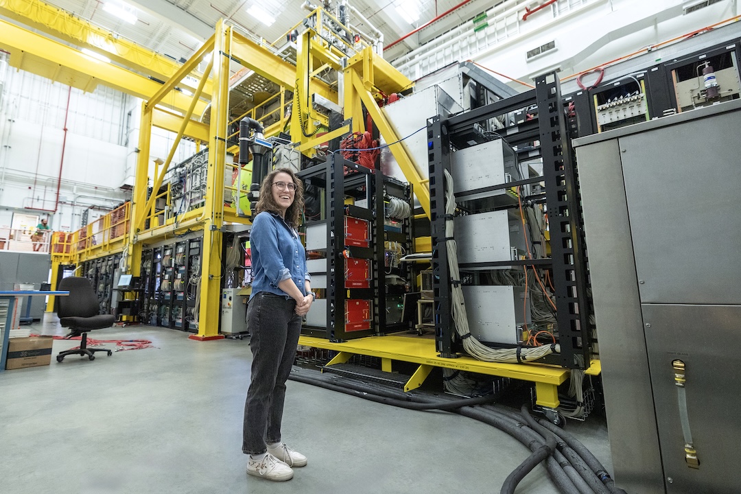 Student stands in front of machinery in lab