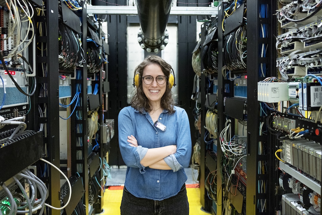 Student stands in front of machinery in lab